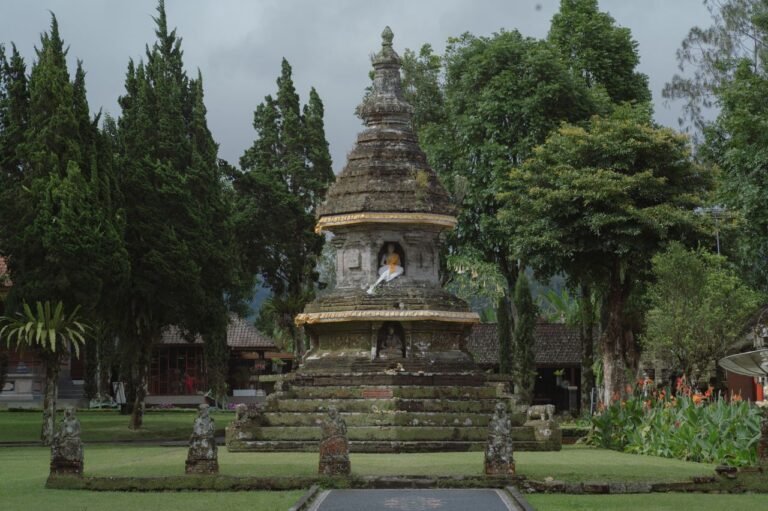A serene ancient Balinese temple with a prominent Buddha statue in a lush garden setting, symbolizing spirituality and peace.